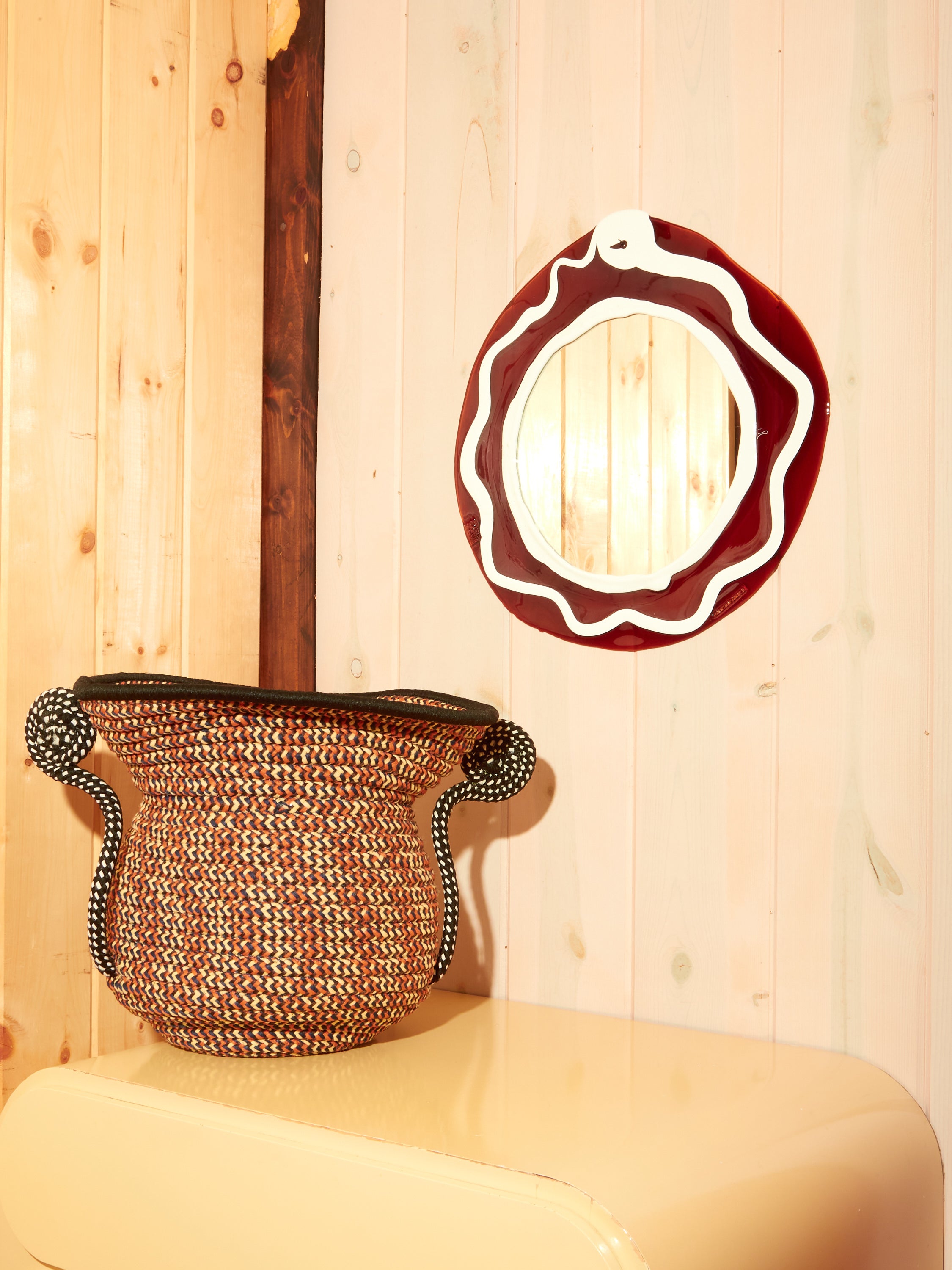 Round Mirror in Brown White hung above a cream dresser. On the dresser is a Giusti Urn by F Taylor.