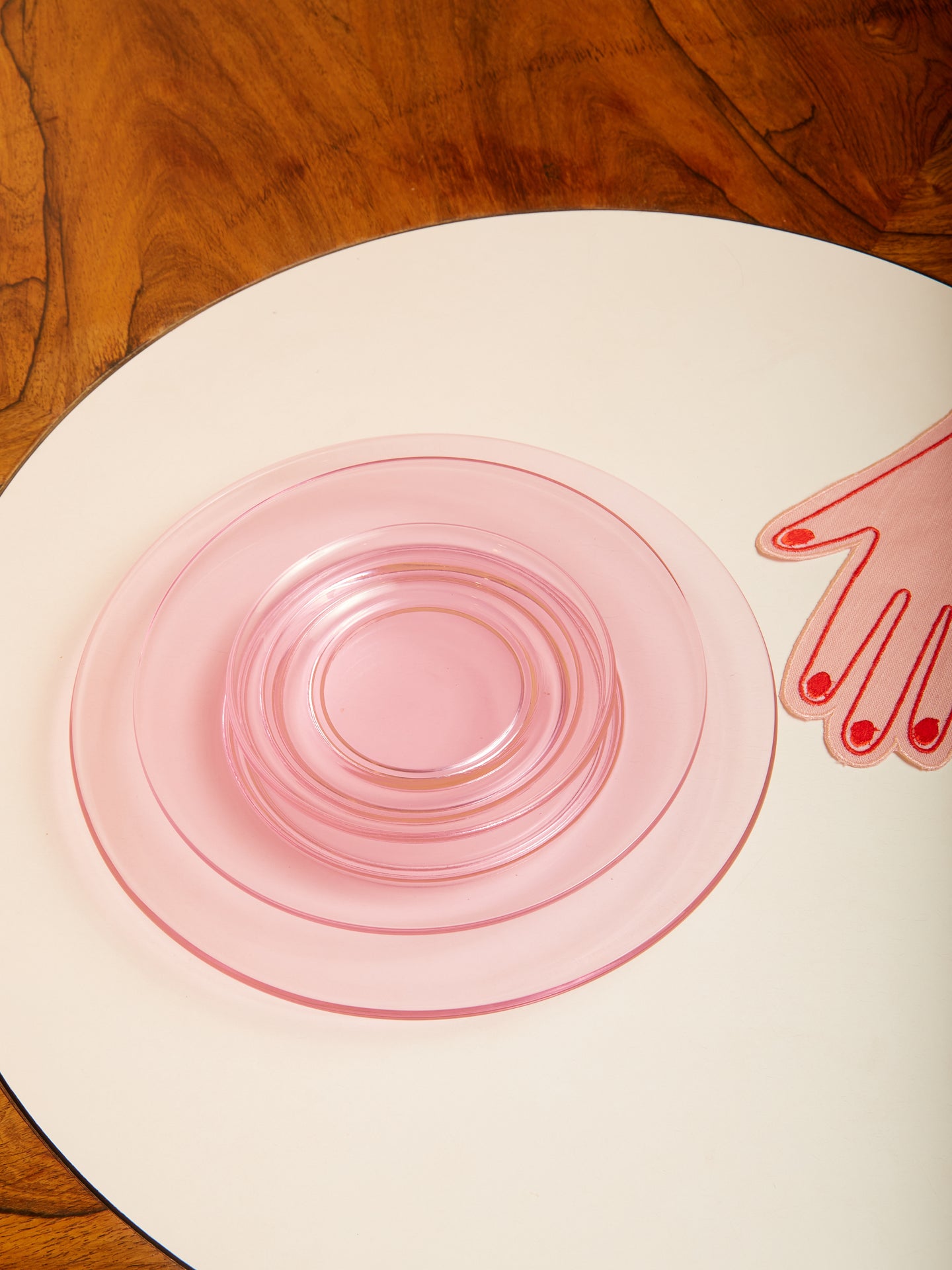 A stack of pink transparent glass plates in various sizes.