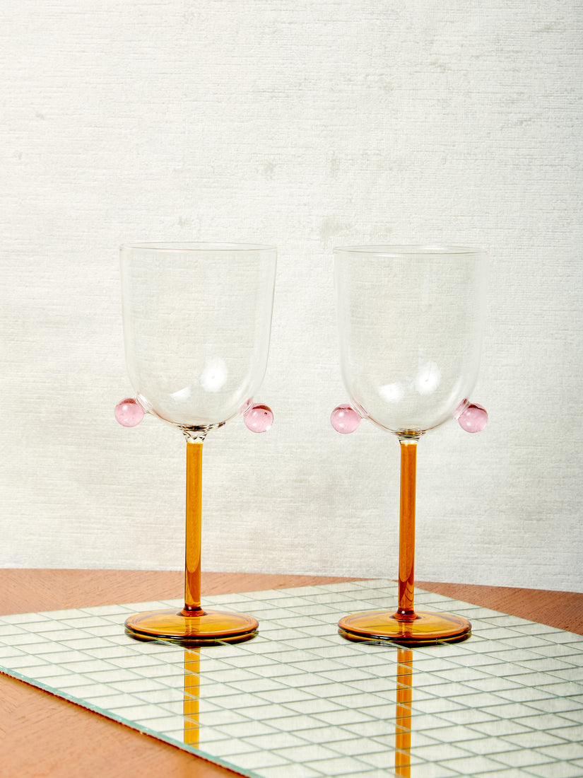 A pair of honey and pink Pompom Wine Glasses by Maison Balzac.