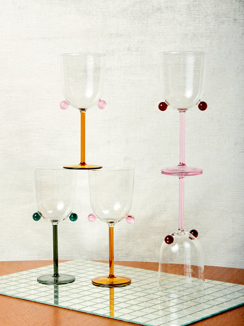 An asymmetrical stack of Pompom Wine Glasses in three different colorways.