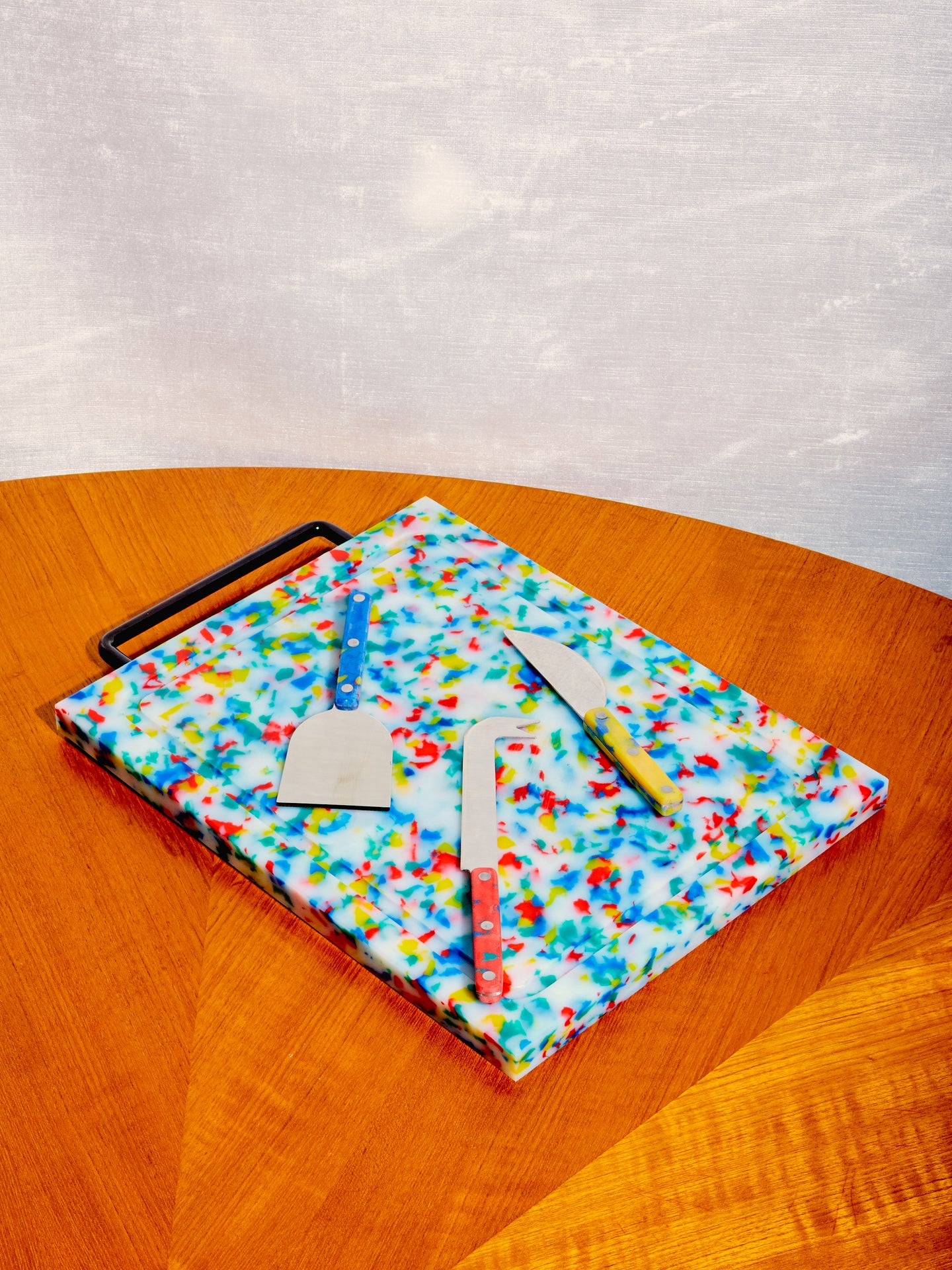 Set of 3 Cheese Knives by Fredericks and Mae atop a Multicolor Chopping Block.