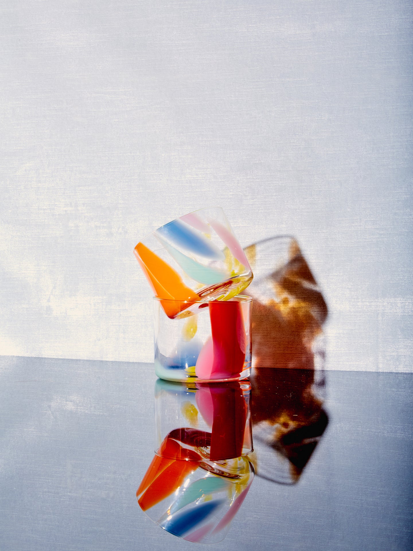 A Rainbow Splash Cup sits atop a matching glass slightly askew.