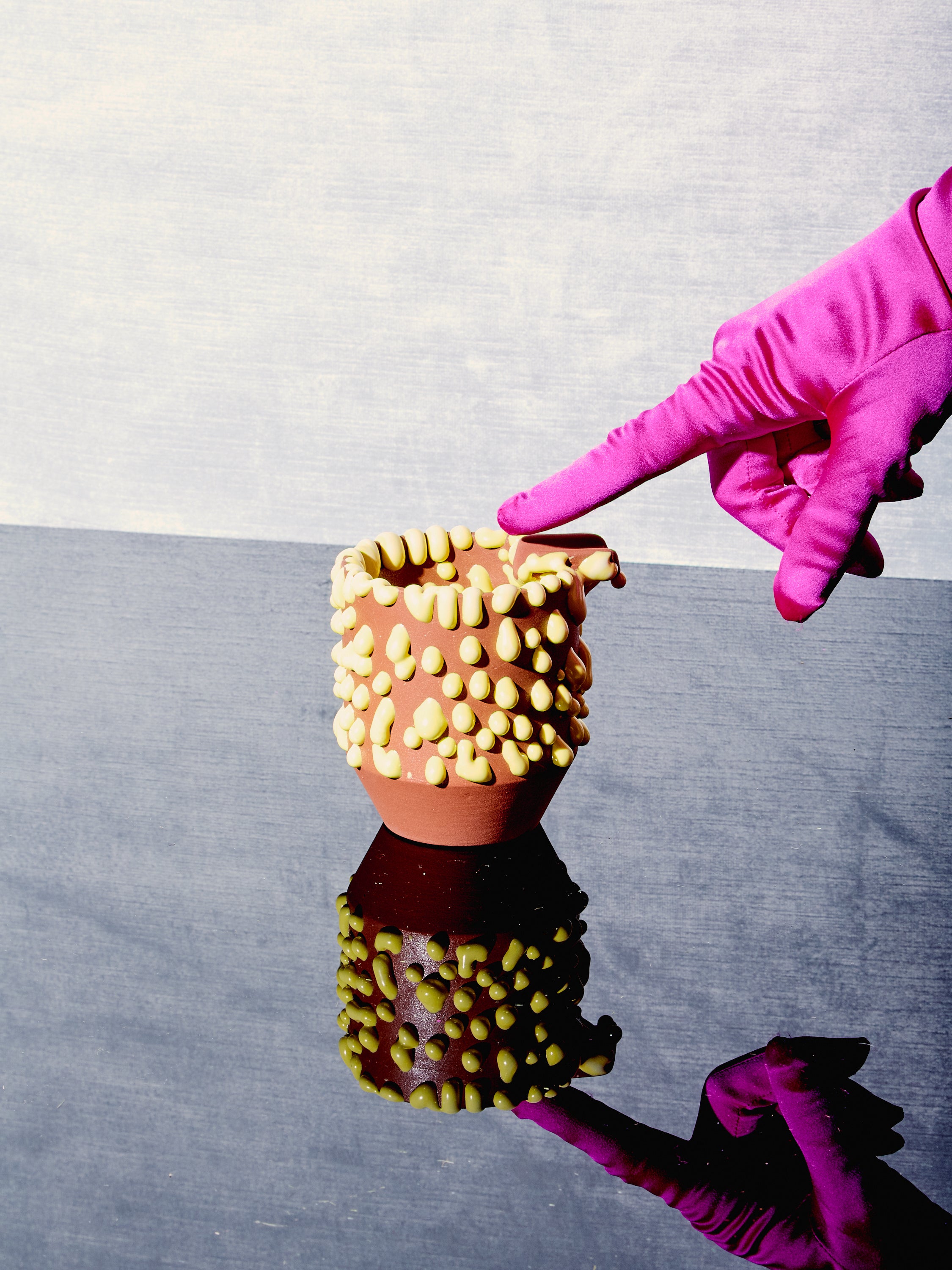 A pink gloved hand points at the Gloopy Ashtray.