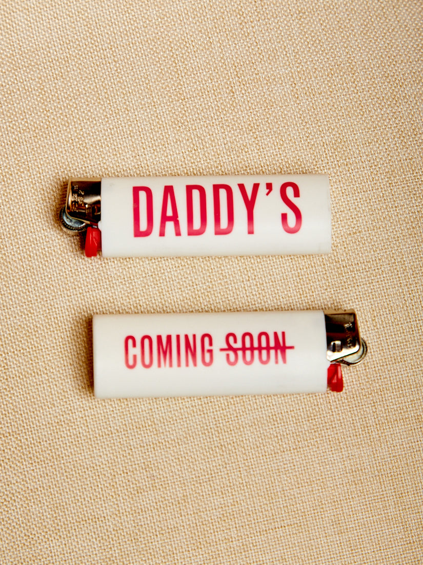 Two white maxi bic lighter with "Daddy's" printed on one side and "Coming Soon" printed on the other.