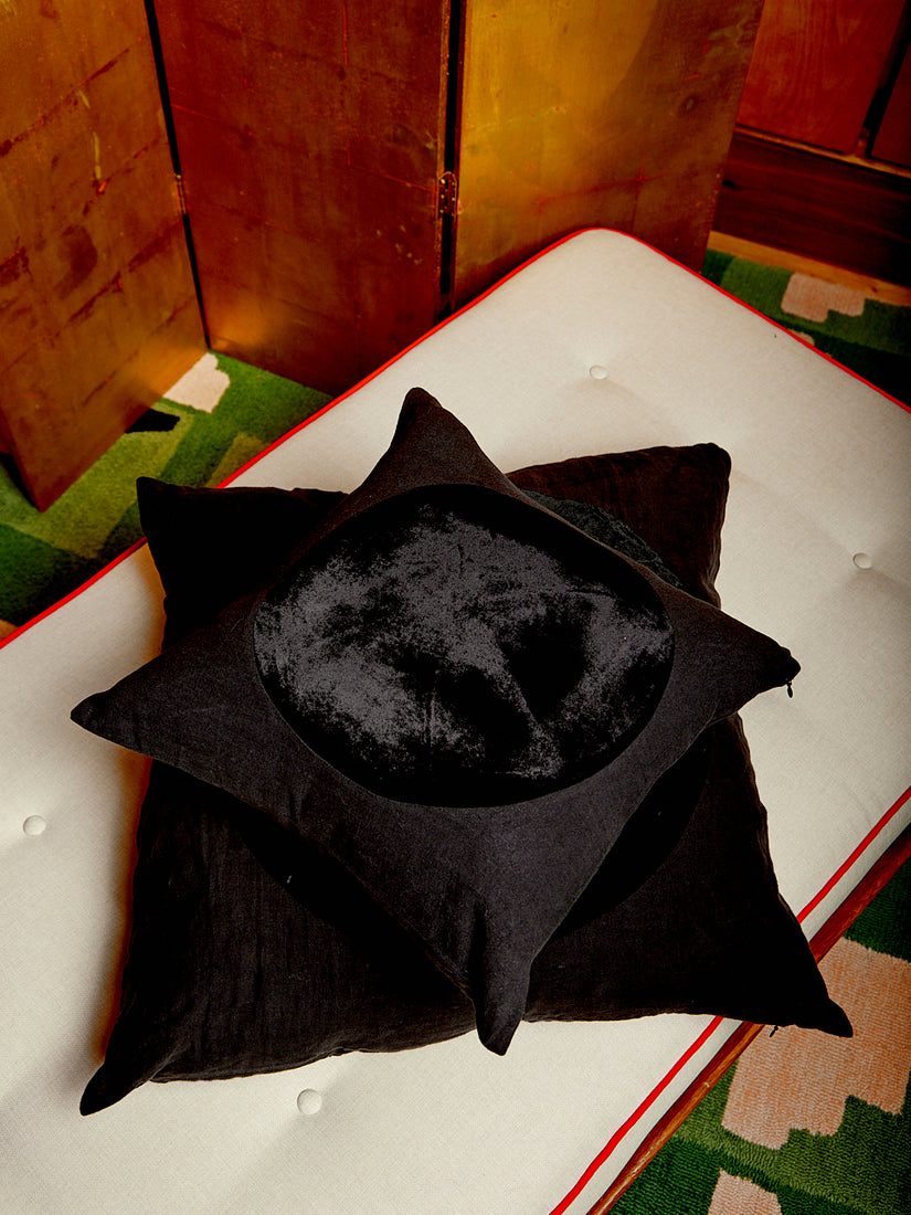 A medium black Velvet Circle Pillow sitting atop a large one.