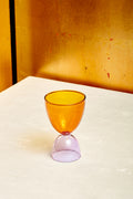 An amber top lavender bottom cocktail glass.