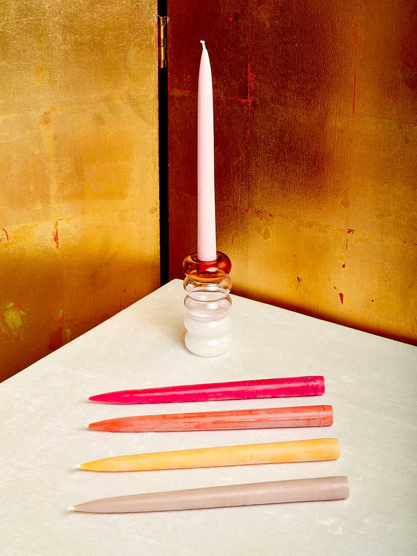 A set of five warm tone taper candles with one inside of a Pauline Candle Holder by Maison Balzac.