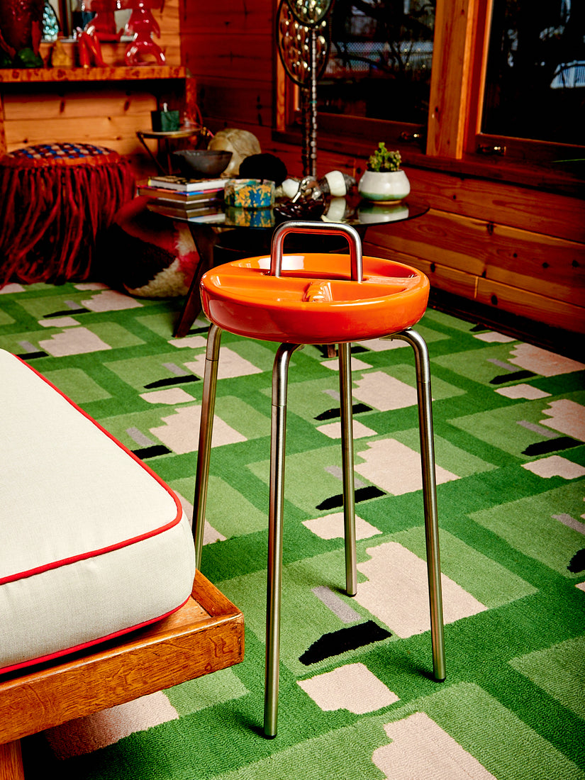 An orange Side Table Ashtray by Houseplant in a wooden living space full of colorful sculptures.