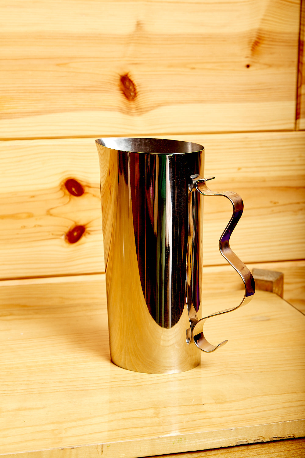 Mirror polished steel pitcher with a wavy handle.