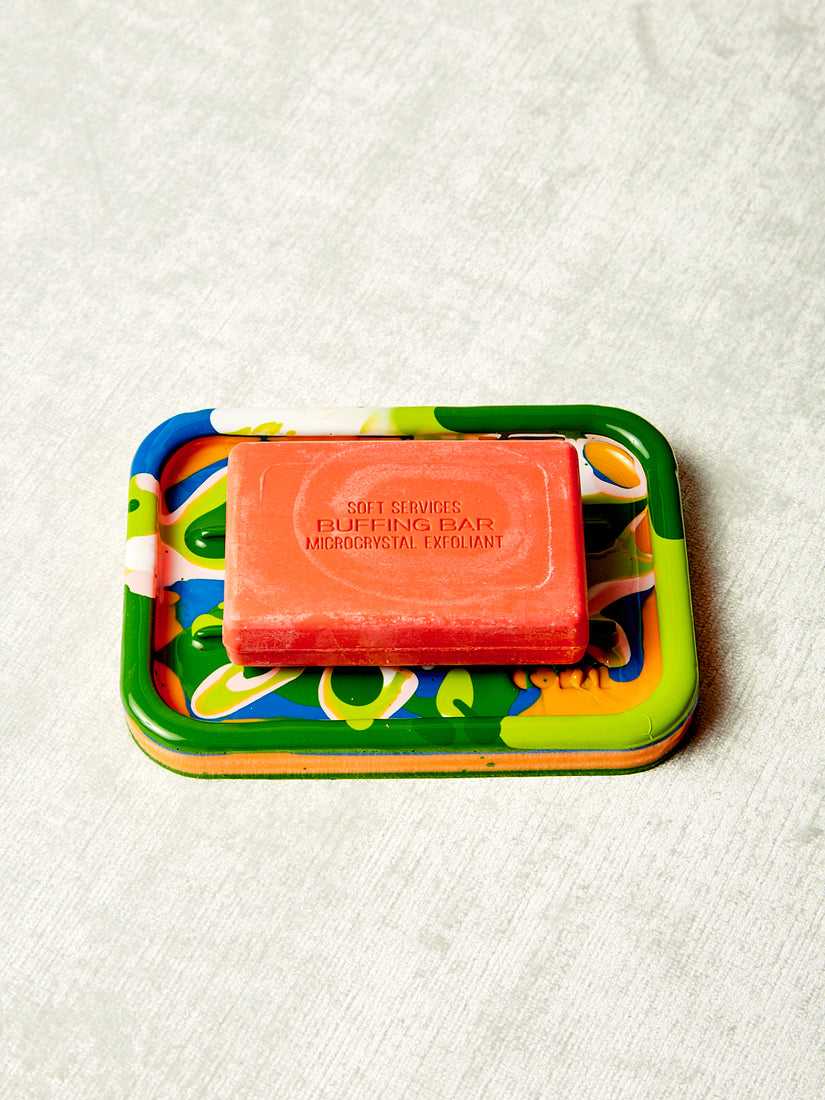 A multicolored resin soap holder with an orange bar of soap.