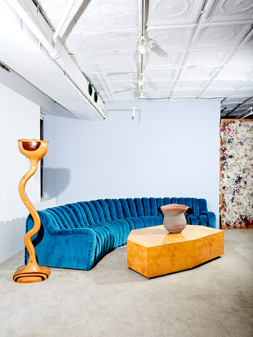 Sculptural Wooden Floor Lamp styled with a blue endless sofa, and burl coffee table.