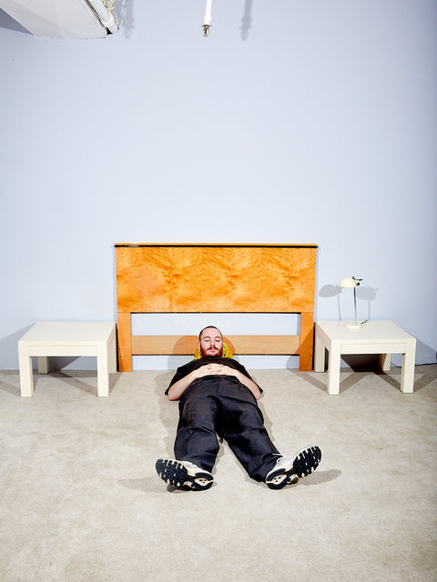 Someone lays on the floor between the two side tables.