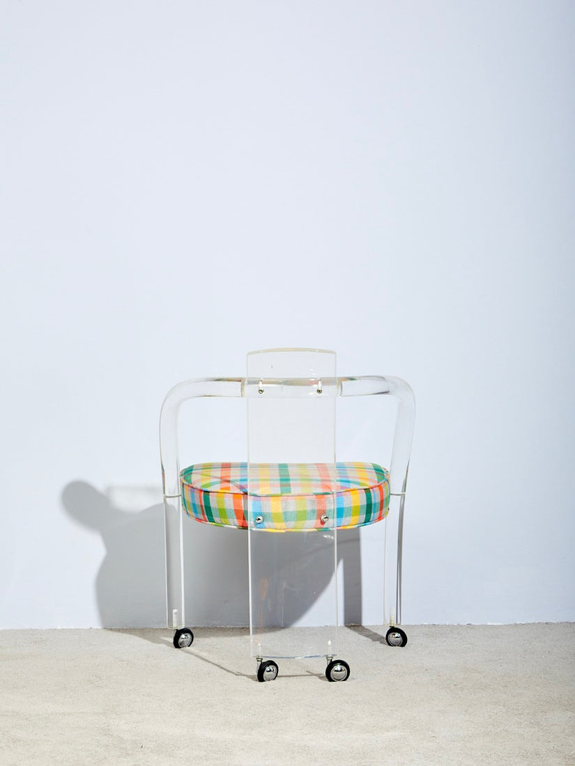 The back side of a Lucite Loop Chair with chrome casters.