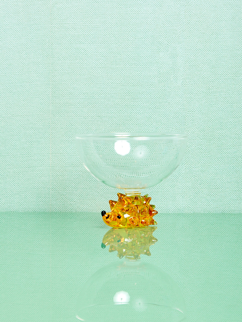 A clear glass bowl thats base is a yellow glass hedghog.
