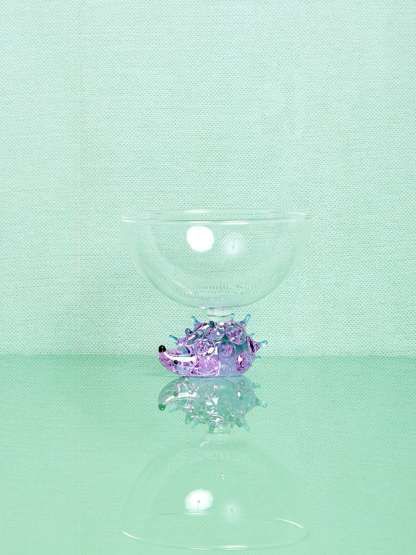 A clear glass bowl thats base is a lavender glass hedgehog.