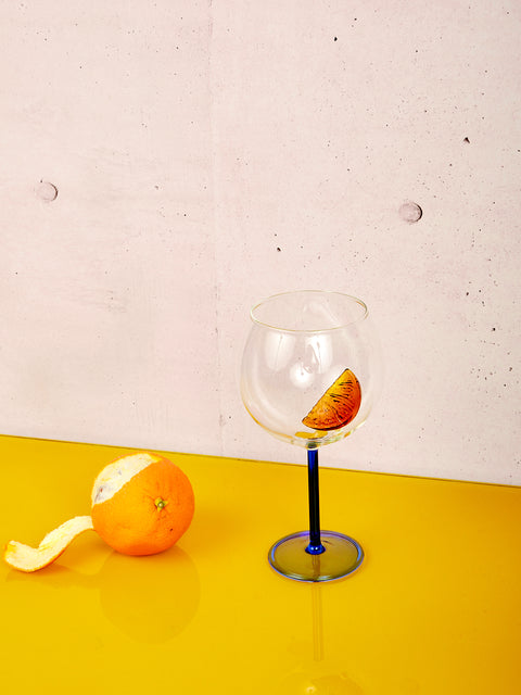 A partially peeled orange sits left of the Spritz Glass by Maison Balzac.