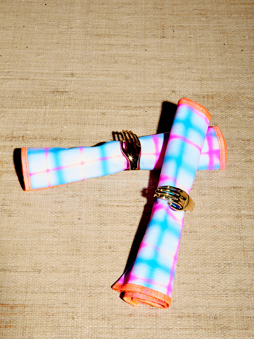 Two vibrant airbrushed napkins are rolled and adorned with Dada's napkin rings.