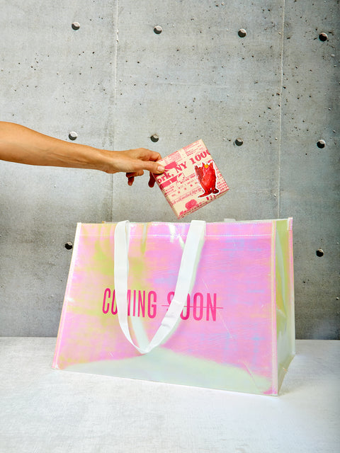 A hand models a gift wrapped item being pulled out of the tote bag.