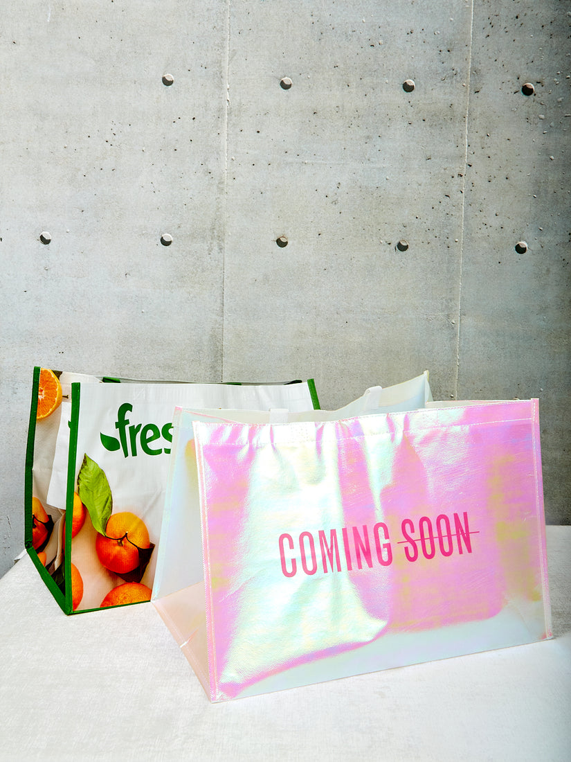 A Coming Soon tote bag sits next to a Fresh Direct tote bag of the same size.