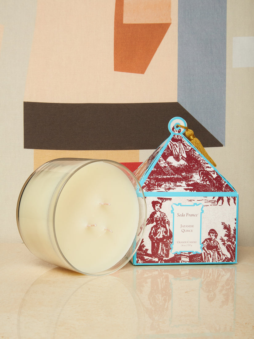 A 26 ounce Japanese Quince candle sits on its side beside its decorative box.