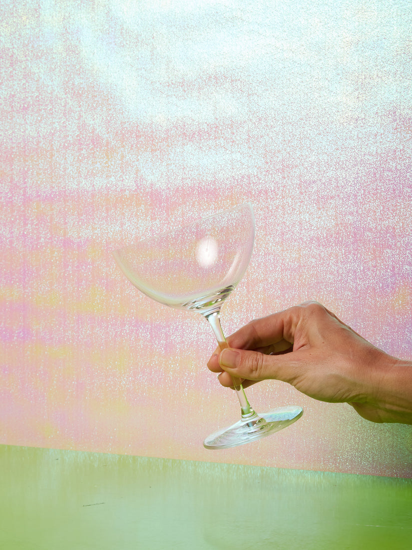 A hand holds a Sonoma Coppa Champagne coupe by its stem.