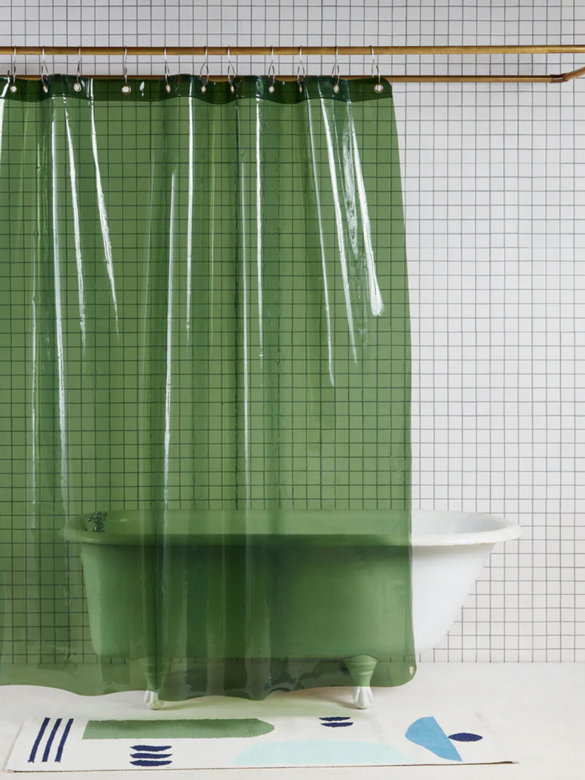A transparent green Sun Shower curtain by Quiet Town in a white tiled bathroom.
