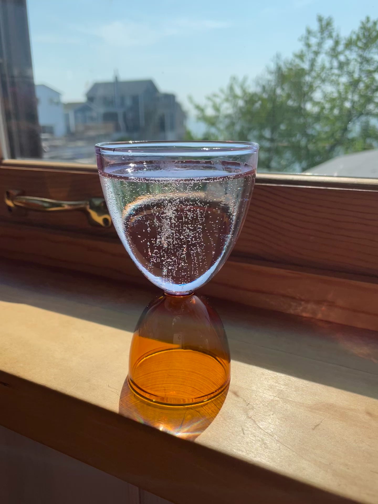 A sparkling beverage lightly bubbles in a lavender top amber bottom cocktail glass.